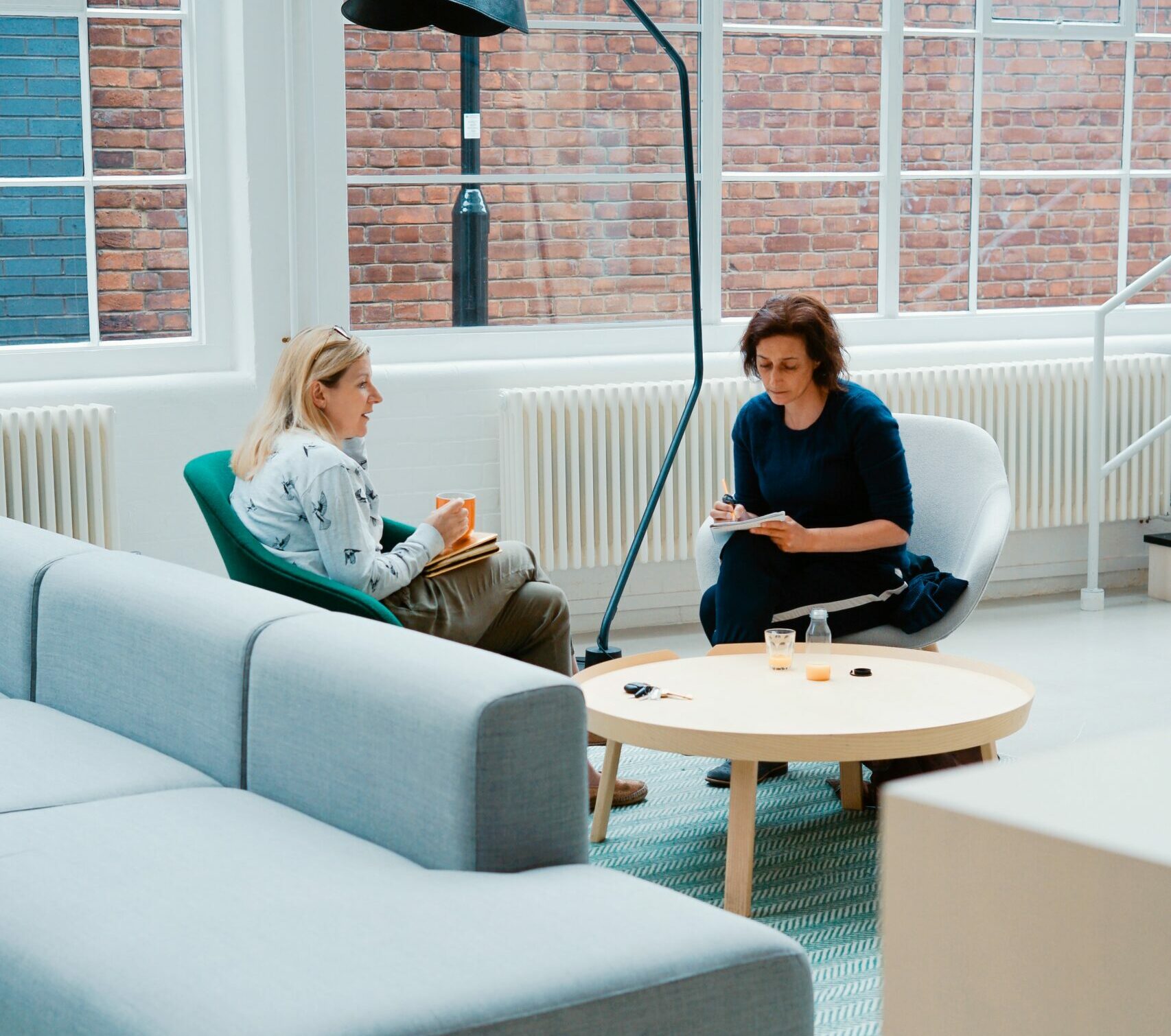 two people talking in arm chairs and working